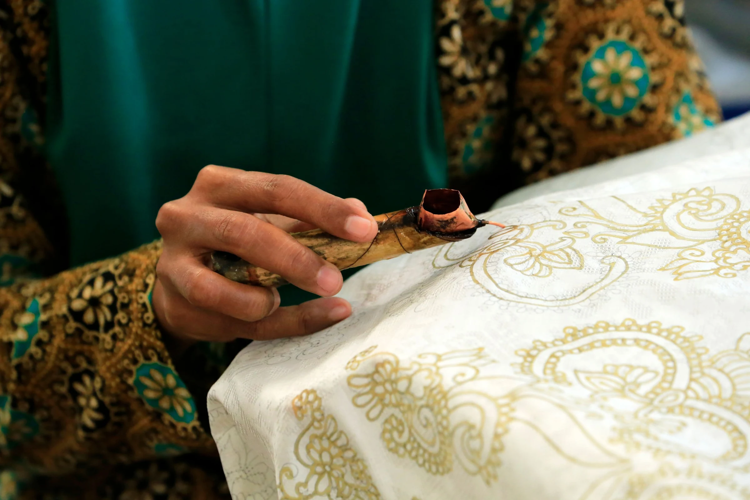 An artisan drawing traditional batik patterns by hand with a wax pen