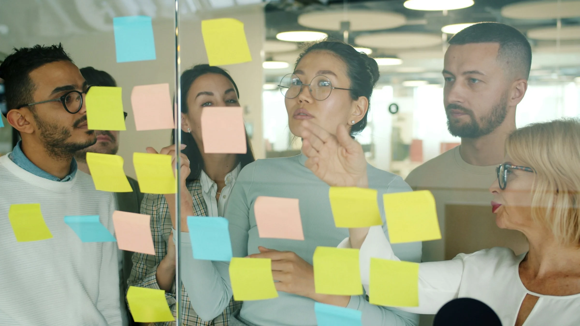 Creative team discussing notes on a glass board